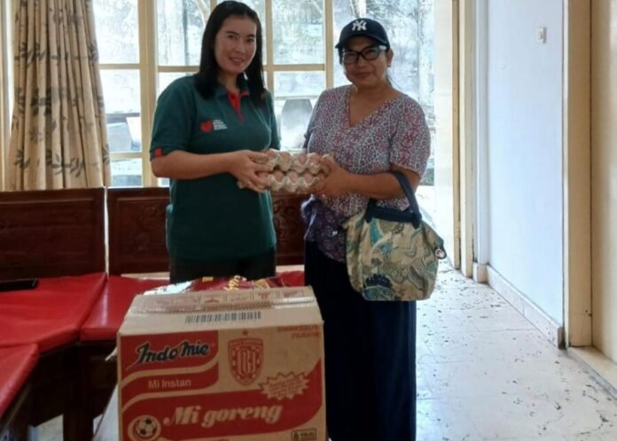 Ibu Era saat menyerahkan bantuan bahan pokok dr seorang dermawan kepada Yunita, petugas Rumah Singgah Kabupaten Jembrana.